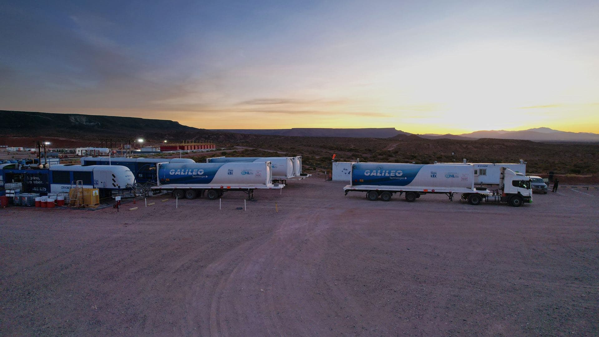 Modular liquefaction equipment and ISO LNG tanker trailers staged in an open yard at dusk.