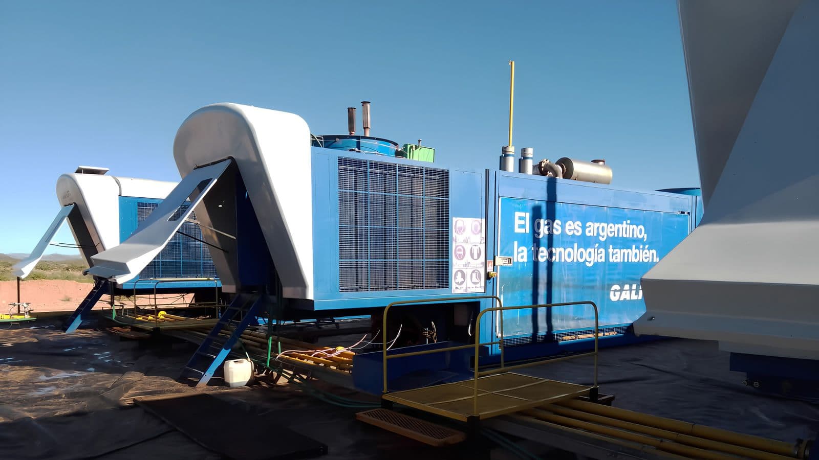 Blue modular liquefaction equipment unit with walkway and condenser housing, installed outdoors.